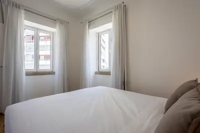 a corridor of a hallway with white walls and wooden doors at Carmo Suites in Faro