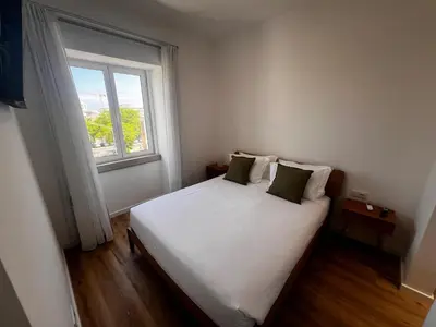 a bedroom with a white bed with a window at Carmo Suites in Faro