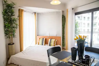 a bedroom with a bed and a table and a window at Apartamento Dubai By Garvetur in Quarteira