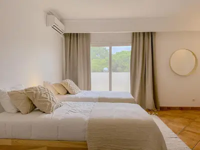 two beds in a bedroom with a large window at Casa Vaga - Garrão beach House