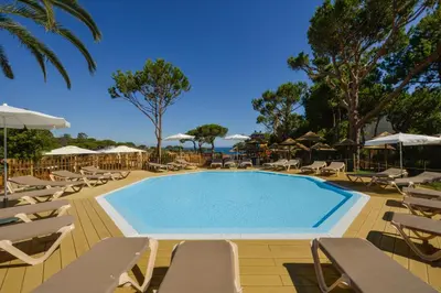 a swimming pool with chairs and umbrellas at 3HB Falesia Beach in Albufeira