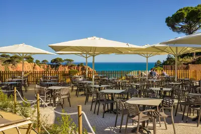 a bunch of tables and chairs with umbrellas at 3HB Falesia Beach in Albufeira