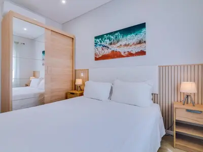 a bedroom with a white bed and a television on the wall at Casa da Avó Marquinhas in Quarteira