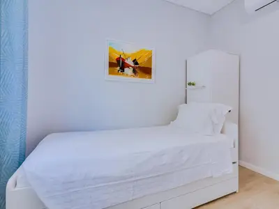 a white bedroom with a white bed and a mirror at Casa da Avó Marquinhas in Quarteira