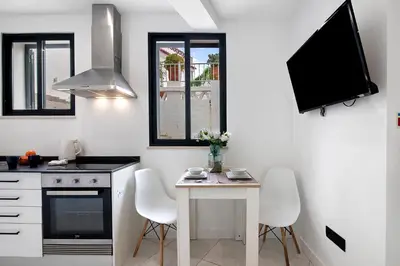 a kitchen with a table and a tv on the wall at Mi Casa Es Su Casa Nº2 in Albufeira