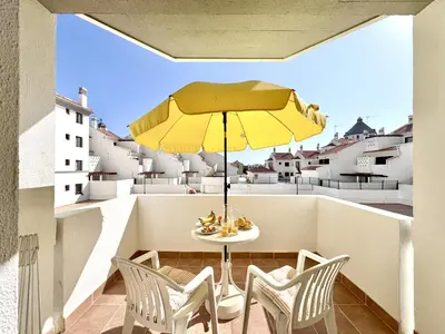 a table and chairs on a balcony with a yellow umbrella at Vilamoura Central 12 With Pool by Homing in Vilamoura