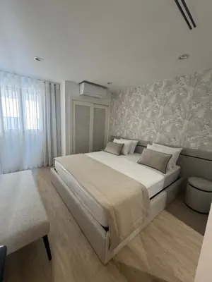 a white bedroom with a large bed and a window at HC2 Village Vilamoura in Quarteira