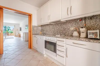 a kitchen with white cabinets and a tile floor at Coastal Pines by Seareen in Quarteira