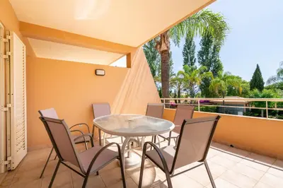 a patio with a table and chairs and a balcony at Coastal Pines by Seareen in Quarteira