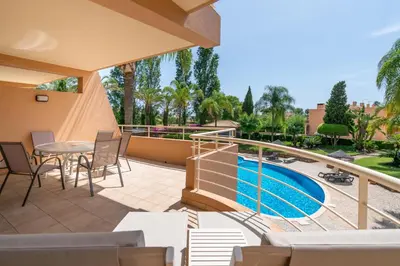 a balcony with a table and chairs and a swimming pool at Coastal Pines by Seareen in Quarteira