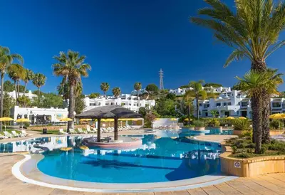 a large blue swimming pool with chairs and umbrellas at Dream House in Clube Albufeira in Albufeira