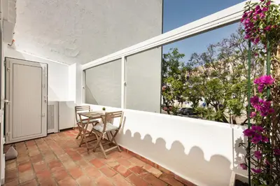 a table with a bottle of wine and two chairs on a balcony at Casinha Amorosa in Faro