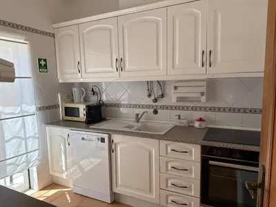 a kitchen with white cabinets and a sink and a microwave at Townhouse Sol&Mar Vilamoura in Vilamoura