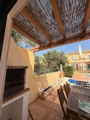 a patio with a fireplace and a wooden pergola at Townhouse Sol&Mar Vilamoura in Vilamoura