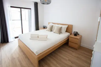 a bedroom with a large bed with white sheets at Go4Portugal - Solaina - Modern Condo with AC and Private Balcony in Albufeira