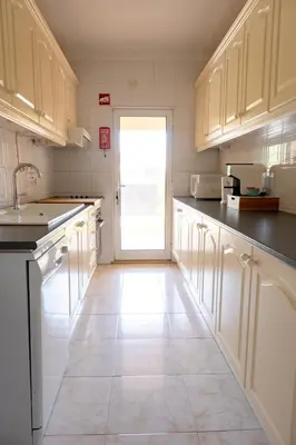 a kitchen with white cabinets and a white tile floor at Apartamento T2 duplex - Vilamoura in Quarteira