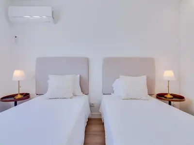two white beds in a room with two lamps at T2 Moderno e Renovado a 500m da praia de Quarteira in Quarteira