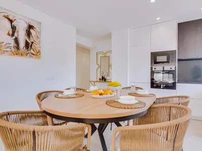 a dining room with a wooden table and chairs at T2 Moderno e Renovado a 500m da praia de Quarteira in Quarteira