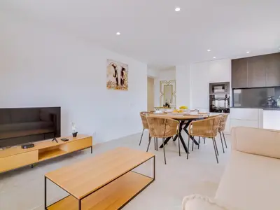 a kitchen and living room with a table and chairs at T2 Moderno e Renovado a 500m da praia de Quarteira in Quarteira
