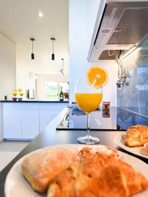 a plate of bread and a glass of orange juice at Oura Modern Poolside Condo by BeCherish in Vale de Pedras