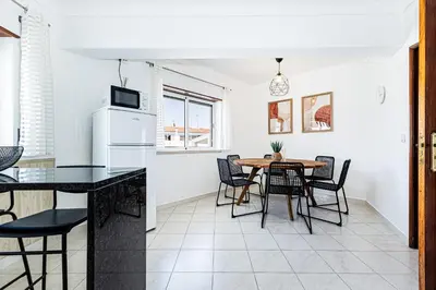 a kitchen and dining room with a table and chairs at O Canto do Oceano T2 Albufeira in Albufeira