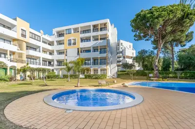 an apartment complex with a swimming pool in front of a building at 2 BDR Flat With Pool in Vilamoura by LovelyStay in Quarteira