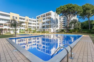 a swimming pool in front of a building at 2 BDR Flat With Pool in Vilamoura by LovelyStay in Quarteira