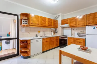 a kitchen with wooden cabinets and white appliances at 2 BDR Flat With Pool in Vilamoura by LovelyStay in Quarteira