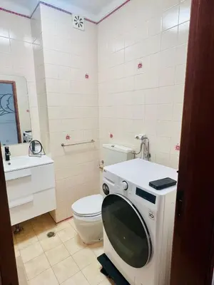 a bathroom with a toilet and a washing machine at Milennium Holiday Apartment in Quarteira