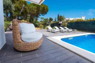 a wicker chair sitting next to a swimming pool at Balaia Retreat - Nature & Beach in Olhos de Água
