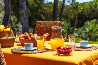 a table with orange juice and baskets of food at Balaia Retreat - Nature & Beach in Olhos de Água