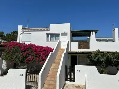 a white house with pink flowers on the stairs at White House By FHR in Quarteira