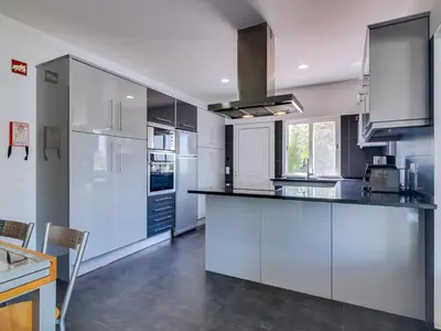 a kitchen with white cabinets and a black counter top at Villa Brown's with Private Pool in Vilamoura in Quarteira