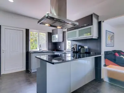 a kitchen with white cabinets and a black counter top at Villa Brown's with Private Pool in Vilamoura in Quarteira
