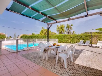 a white table and chairs under a roof with a pool at Villa Brown's with Private Pool in Vilamoura in Quarteira
