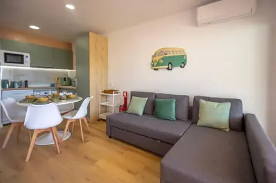 a living room with a gray couch and a kitchen at NEW! Dream Terrace Albufeira Ocean and Pool Views in Bicas