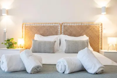 a white bedroom with towels on a bed at Magna Studio in Albufeira