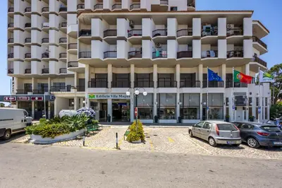 a large building with cars parked in front of it at Magna Studio in Albufeira