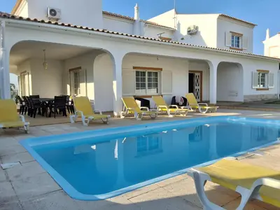 a swimming pool with chairs and a house at Villa Relax in Bicas