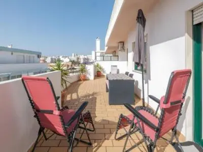 two chairs and an umbrella on a balcony at Faro Charm Apartment - City Center in Faro