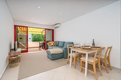 a living room with a table and a blue couch at HostWise - Sunny Escape with a Pool & Balcony in Vilamoura