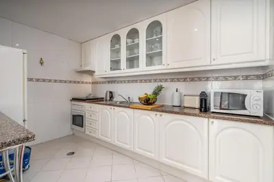 a white kitchen with white cabinets and a sink at HostWise - Sunny Escape with a Pool & Balcony in Vilamoura