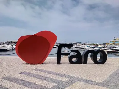 a red heart and a bench in front of a marina at Simply House in Faro