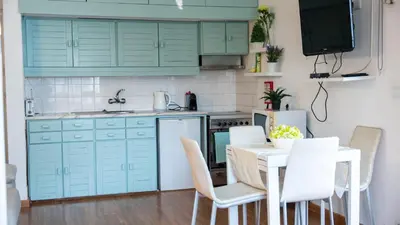 a kitchen with green cabinets and a table and chairs at Bayview Old Town Beach Apartment in Albufeira