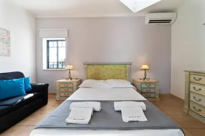 a bedroom with a large bed and a couch at Tangerine Apartment by HelloVacations in Albufeira