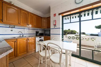a kitchen with wooden cabinets and a white table and chairs at Tangerine Apartment by HelloVacations in Albufeira