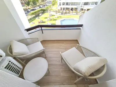 a balcony with chairs and a table and a pool at Vilamoura Collection in Quarteira