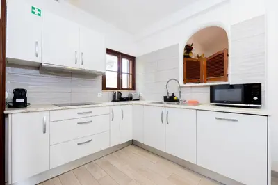 a kitchen with white cabinets and a sink and wooden floors at Casa Gralheira - Private Pool & Sea View in Albufeira