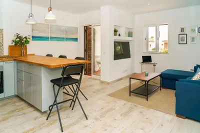 a kitchen and living room with a blue couch at Apartment Maresias 120 m Oura Beach By Bedzy in Albufeira