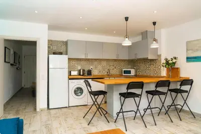 a kitchen with a counter and four stools at Apartment Maresias 120 m Oura Beach By Bedzy in Albufeira